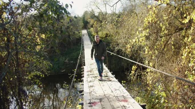 一个秋天的夜晚，一名男性游客沿着一座悬吊的木桥散步。