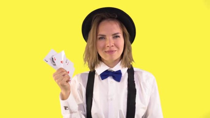 穿着白衬衫，帽子和领结的副主持人展示了扑克牌和微笑。四张王牌，女人眨眼。黄色背景