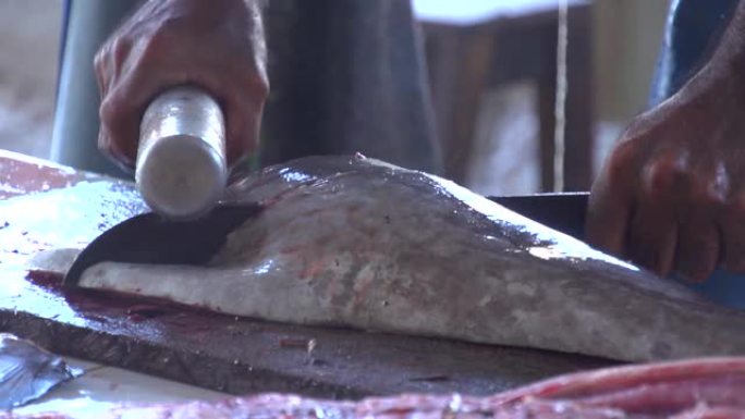 渔民在传统的鱼市场上用剑和锤子切成新鲜的金枪鱼