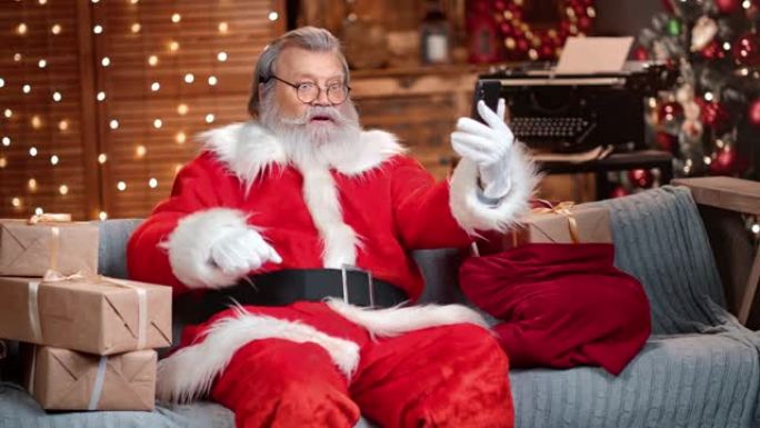 穿着圣诞老人服装的老人在网上聊天，叫圣诞快乐。4k龙红相机