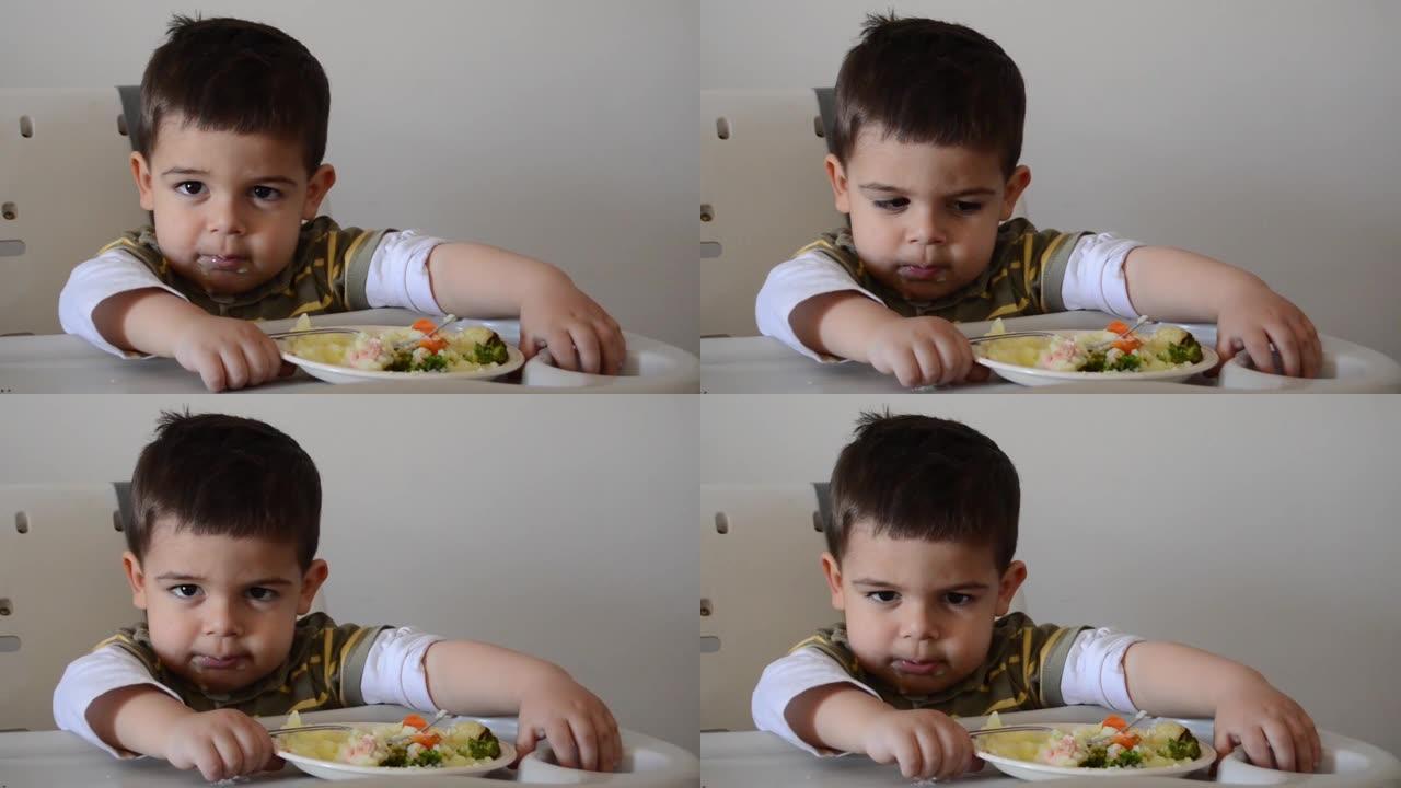 脾气暴躁的两岁男孩玩食物，拒绝吃东西。