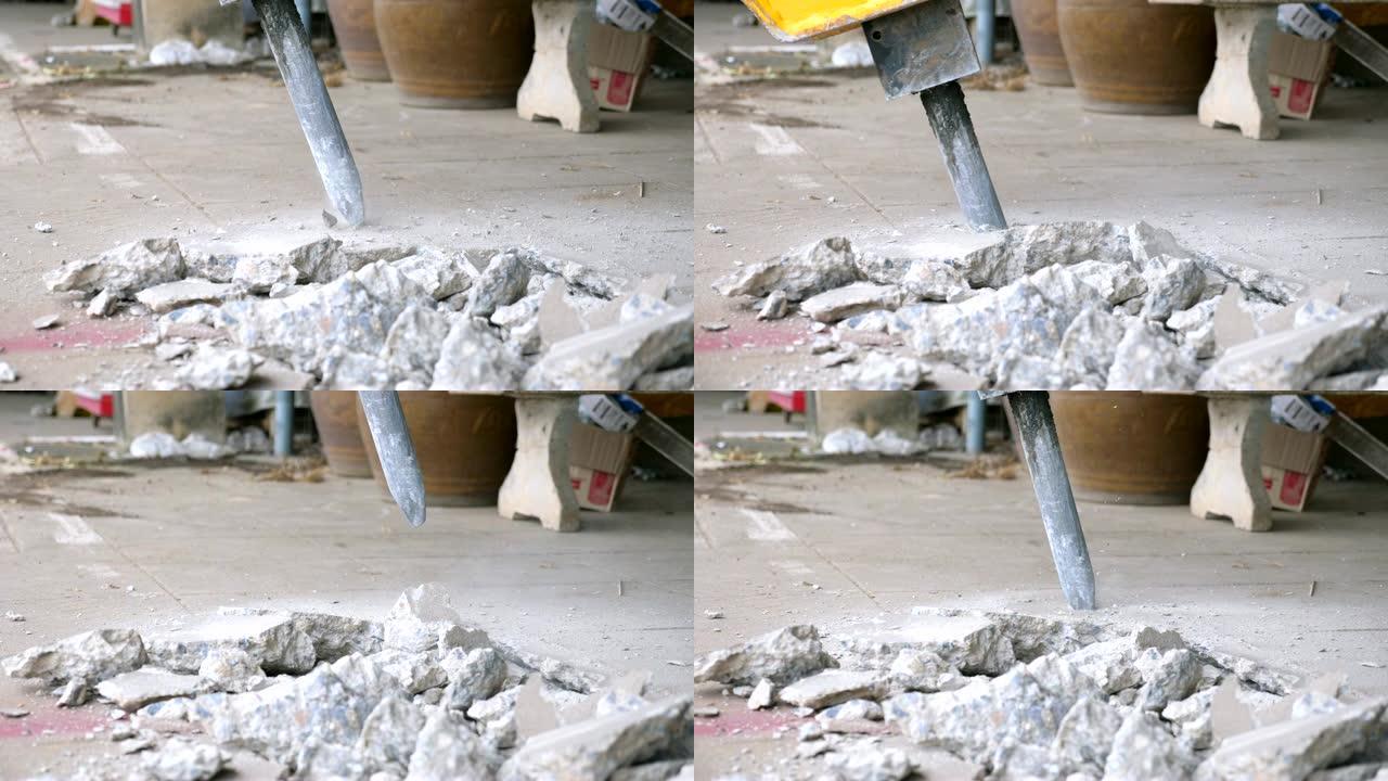 特写手提钻挖掘机在慢动作拍摄中钻孔混凝土地板。