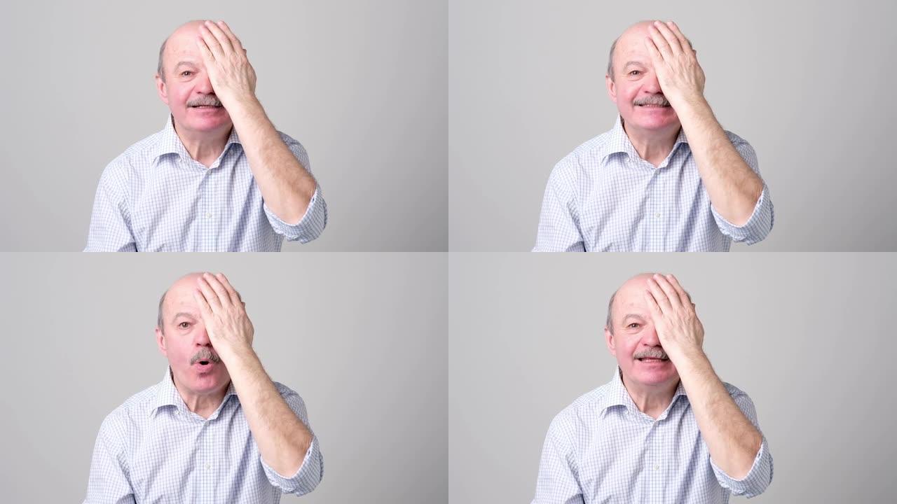 男子在视力检查时遮住一只眼睛试图看字母。