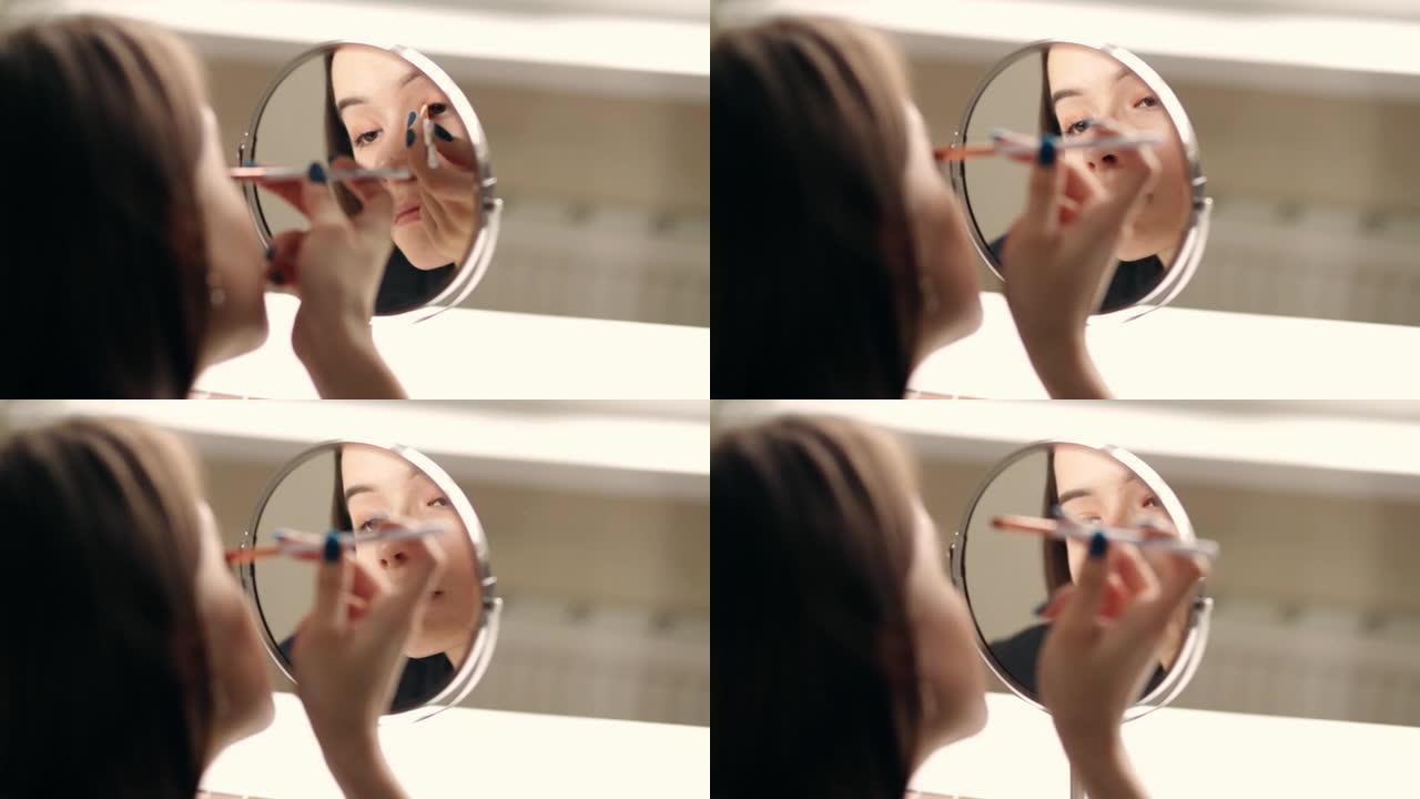 年轻女子照镜子化妆，用眼影画眼睛