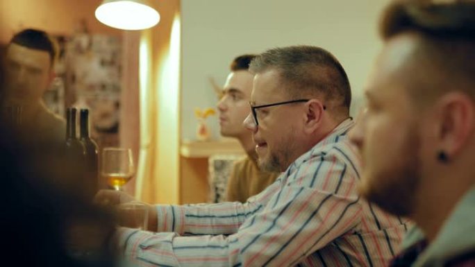 戴眼镜的成年男子在朋友中间吃披萨。男公司正在室内聊天休息。友好的气氛。