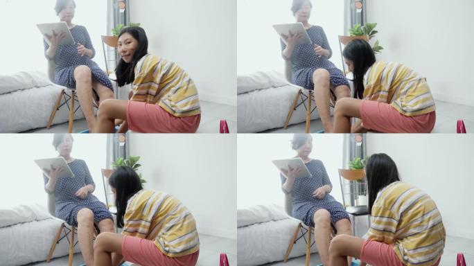 快乐的亚洲母亲使用数字平板电脑，而女儿在脚趾甲绘画前清洁脚，生活方式概念。
