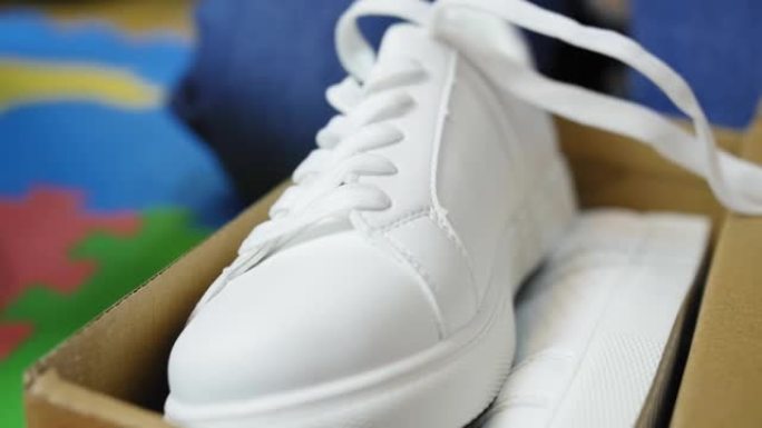 关闭白色新运动鞋。家里地板上有鞋子的盒子。
