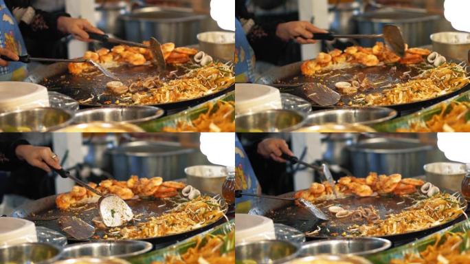 慢动作，厨师在热炒锅上烤鱿鱼和章鱼。一道大菜，配以美味的沙拉和炸虾
