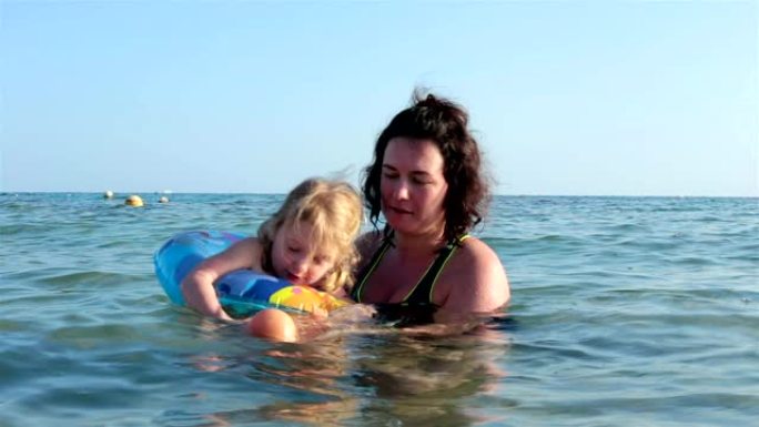母亲和女儿在海里游泳。