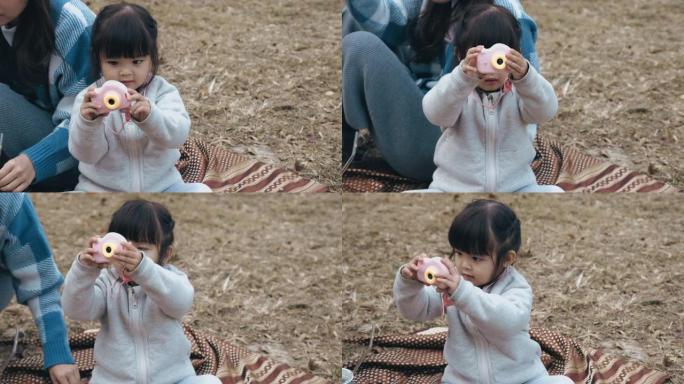 一个亚洲小女孩在公园里玩玩具相机