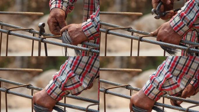 近距离施工工人的手使用钳子工具和铁丝编织金属棒，以在混凝土浇筑之前固定钢筋。建筑施工和行业概念。运动