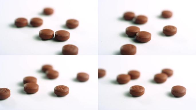 散开的棕色布洛芬药丸的特写镜头，在白色表面上的焦点直接旋转