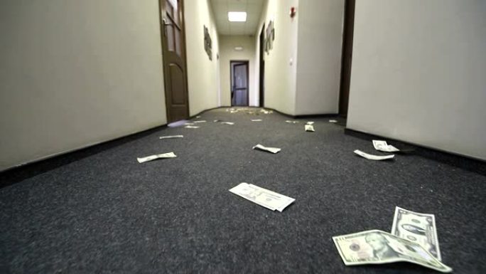 美元钞票散落在酒店或办公室的地板上。账单上的摄像机运动