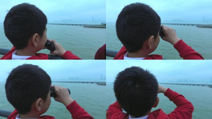 小男孩在游船上用双筒望远镜观察城市景观