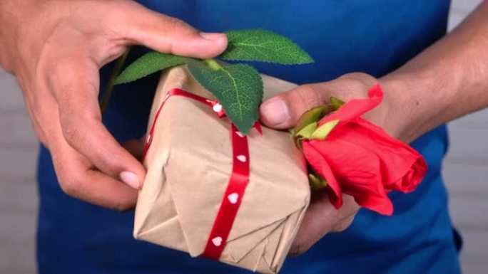 未识别男子手捧玫瑰花和礼品盒特写