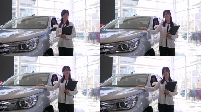 车展，微笑的汽车销售商的肖像亚洲女人在经销商处展示了新车