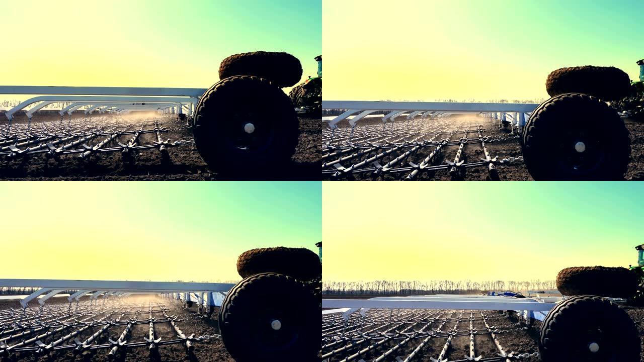 从侧面到耕种机的特写镜头，大轮犁上的拖拉机，用大金属犁耙土，在耕地上扬起大量灰尘，农场肥沃的土地。-