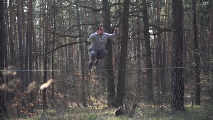 男子在森林中以慢动作在松懈线上跳跃和表演