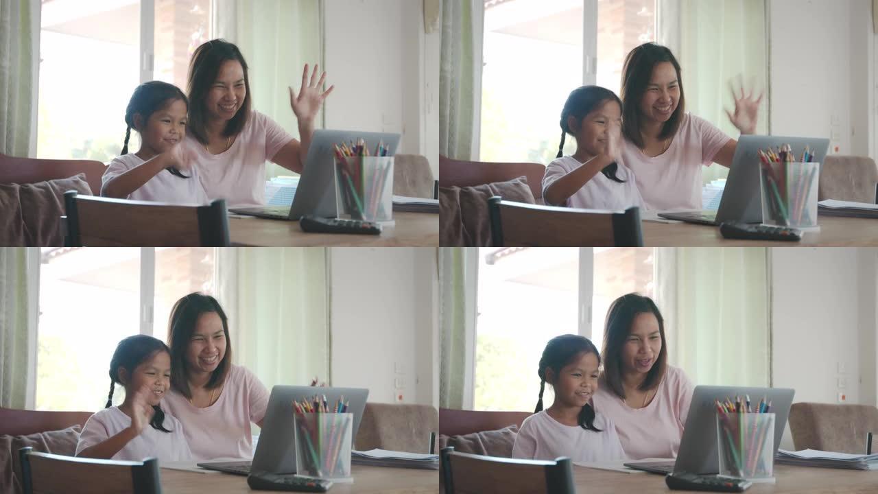 亚洲母女在家用电脑笔记本电脑在线视频通话向朋友问好。由于Covid 19大流行，孩子在家上学，父母在