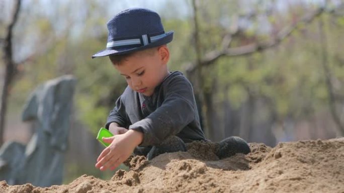男孩在后院用铁锹挖沙堆