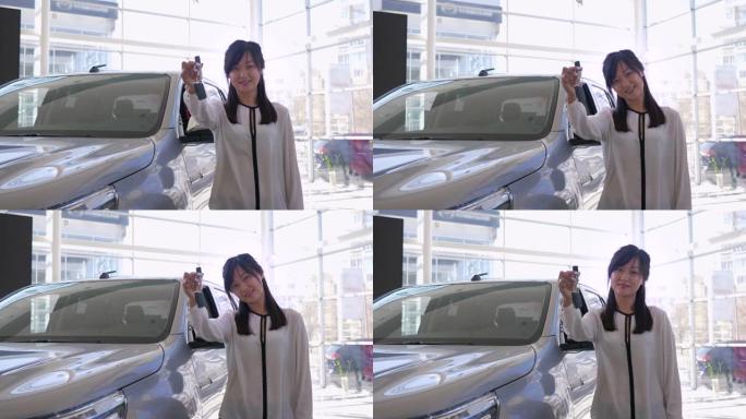 汽车销售中心，专业汽车销售商的肖像亚洲女性手握新车在经销商处销售的钥匙