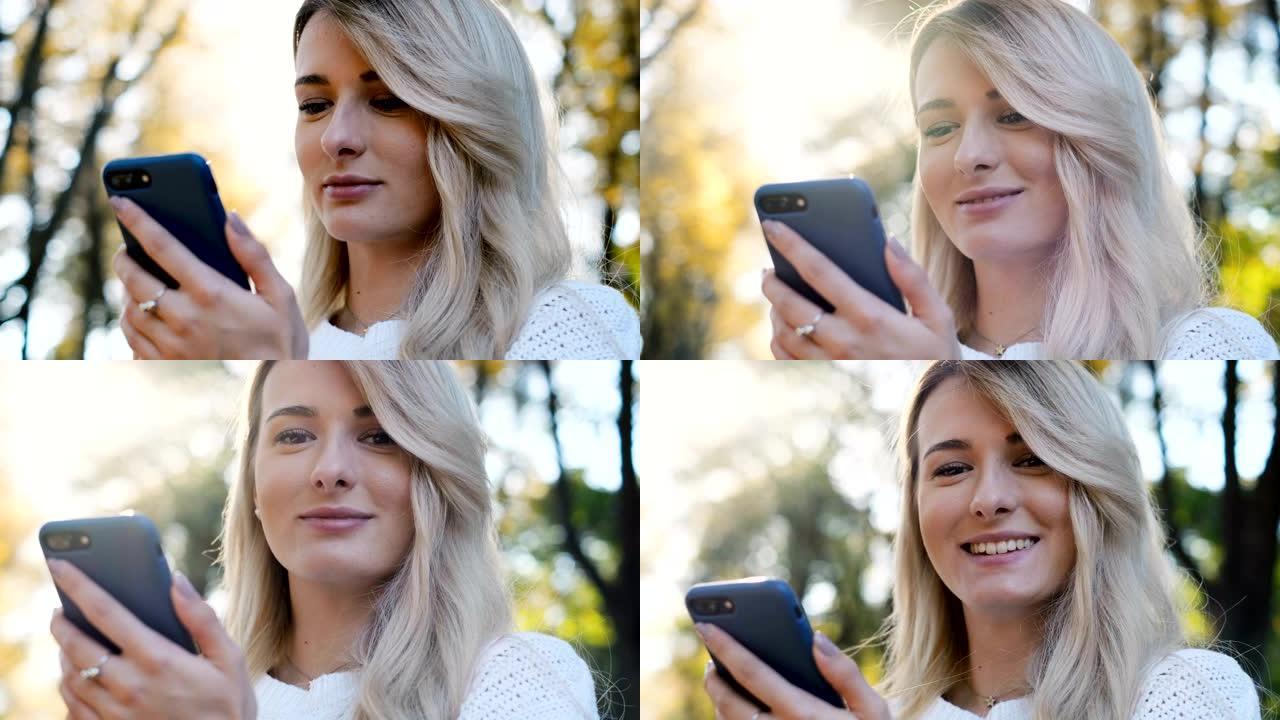 在城市公园中使用智能手机和手机浏览的可爱女孩穿着白色毛衣的特写肖像。
