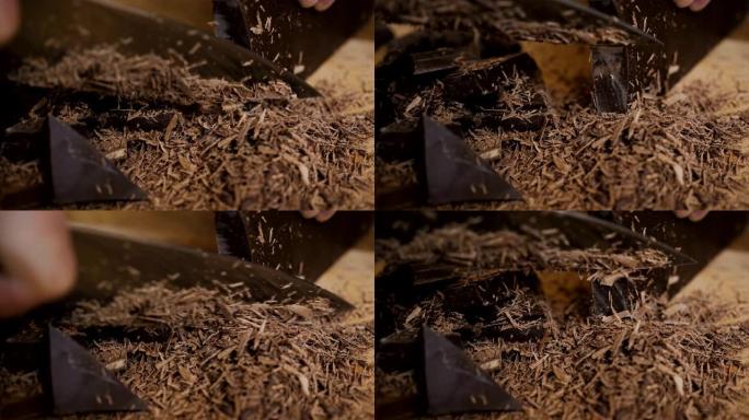 厨房板上切碎的黑巧克力。烘烤时切碎一块巧克力。慢动作。特写。在木制桌子上的砧板上切碎巧克力。特写。