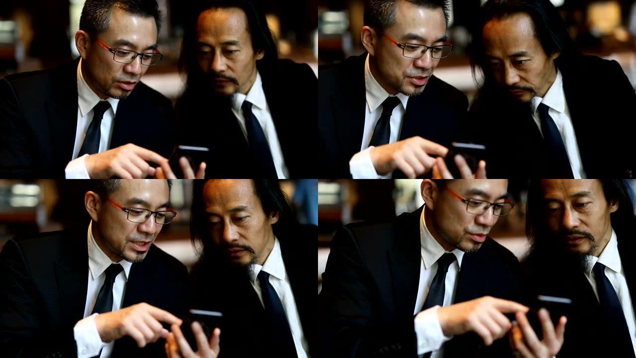 两名商人在咖啡馆一起使用智能手机