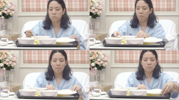 亚洲妇女病人在医院的床上吃饭