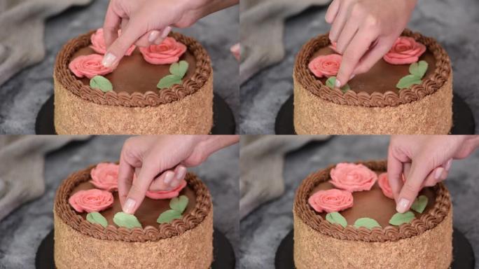 女性双手用奶油花朵和叶子装饰自制的基辅蛋糕