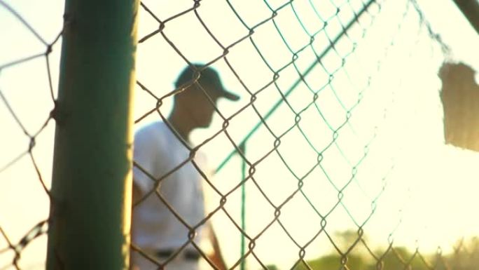 棒球运动员在日落时在空旷的棒球场上练习击球