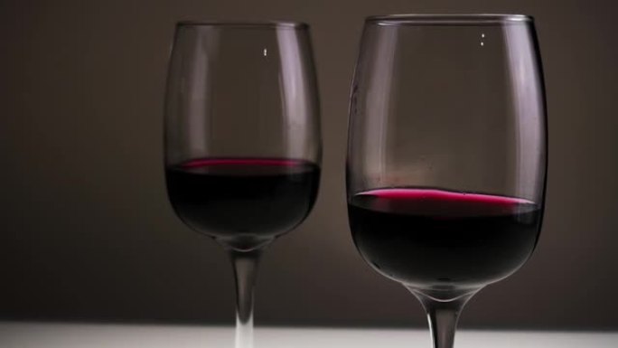 红酒，两杯在黑暗背景下的桌子上。慢动作。