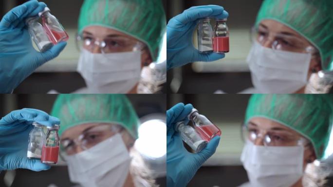 女生物物理学家在保护无菌的衣服手里拿着两个透明的小瓶，看着他们，小瓶用药粉和红色液体溶液。科学实验在