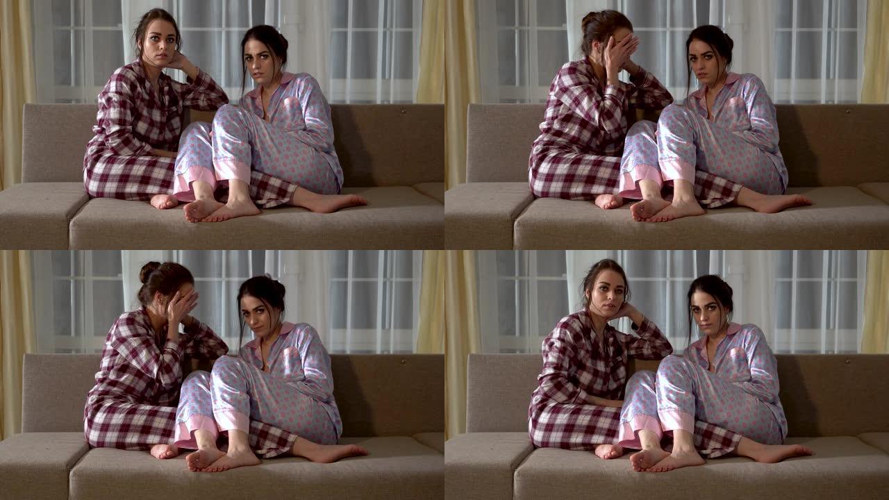 两个穿着睡衣的双胞胎姐妹坐在沙发上，选择在电视上看什么