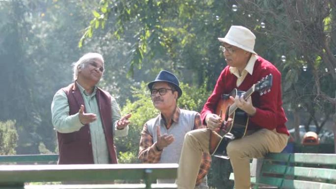 三名老人弹吉他并在公园玩得开心
