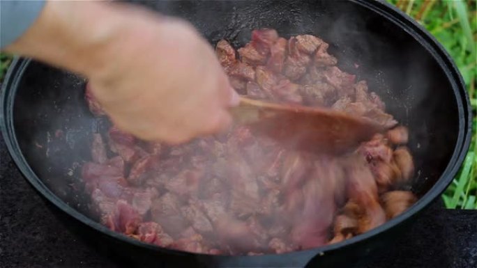 东方菜肴的烹饪过程。红肉在一个大锅里煮沸并在油中炖煮。大型传统亚洲大锅在明火上，称为喀山