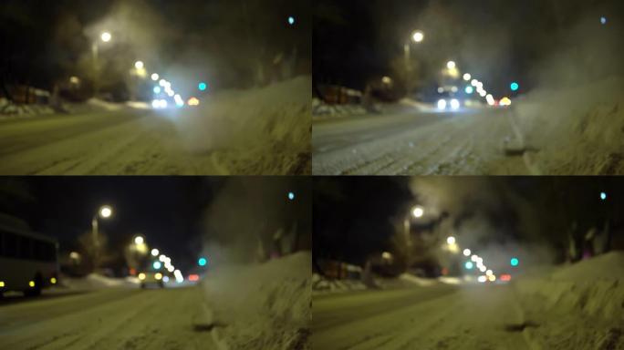 晚上的俄罗斯冬季之路。蒸汽从道路上的下水道炉排出来