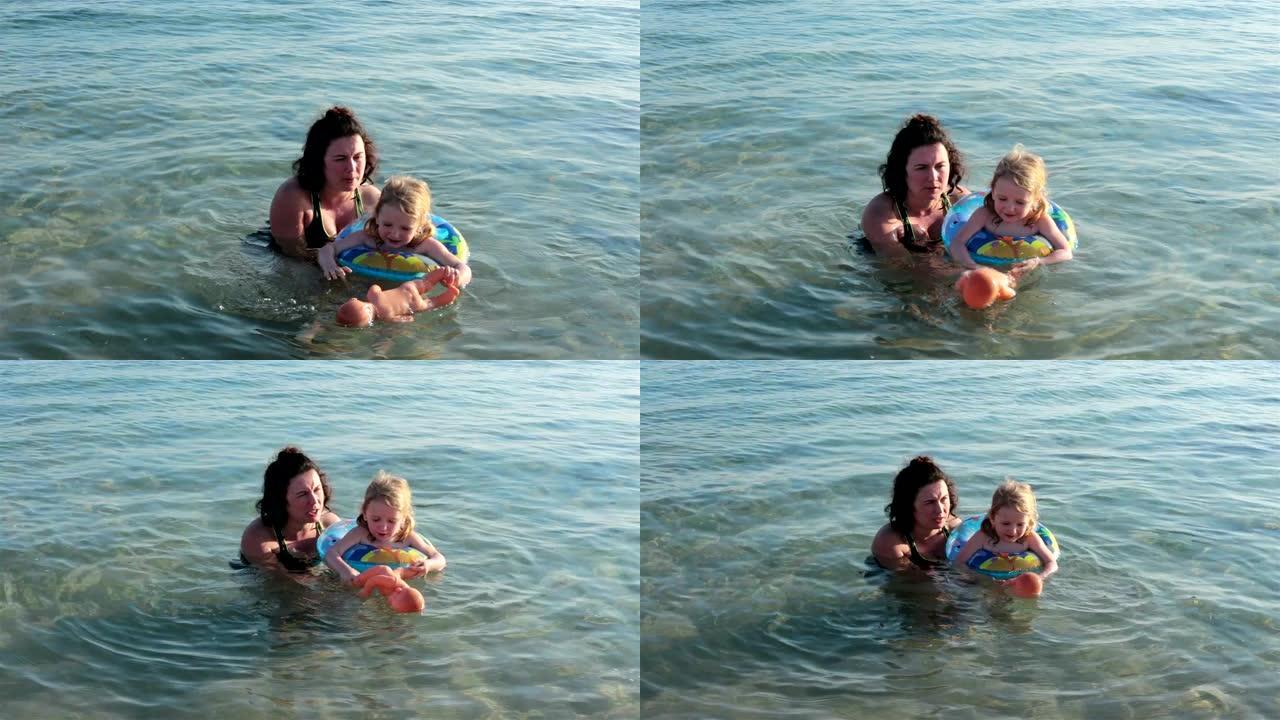 母亲和女儿在海里游泳。