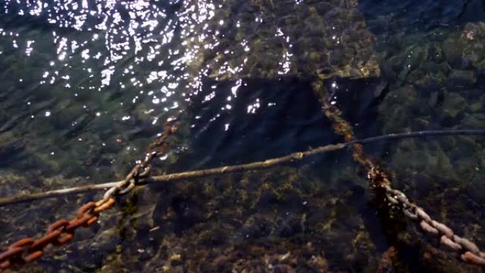 长满藻类的老生锈船链。阳光反射的海水
