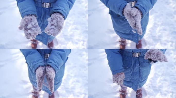 一个戴着粉红色手套的女孩在打雪球后摆脱了粘稠的雪。