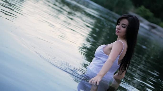 美丽的黑发女孩，长发站在湖里。慢动作。