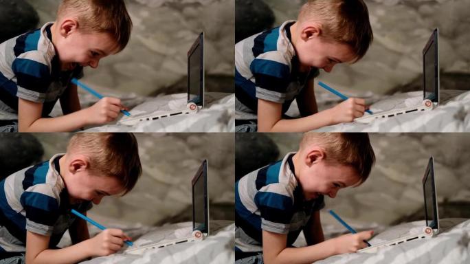 一个小男孩玩电脑。用铅笔在键盘上写字。厌倦了远程学习，自我放纵，疯狂。