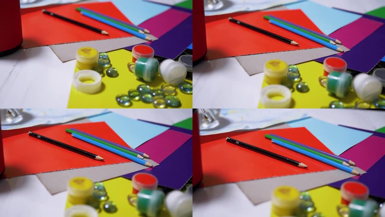 桌子上随机排列着鳄梨颜料、铅笔、刷子、彩色纸