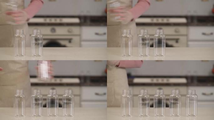 一个女人准备干净的玻璃瓶来填充它的特写演示视频。自制食品准备