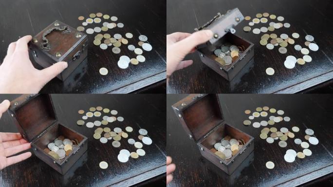 手正在打开带有棕色背景古董硬币的旧棺材，特写。一堆硬币概念