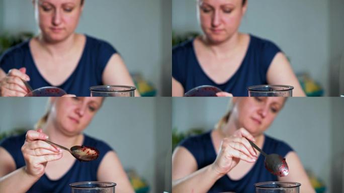 健康饮食的概念。一个女人的特写镜头把一勺水果和浆果泥放在搅拌机里。