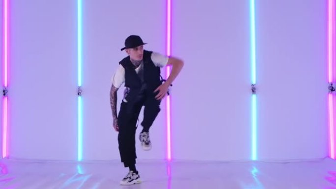 专业嘻哈舞者在工作室里对着明亮的霓虹灯练习街舞元素。时尚男子在慢动作中大力跳舞