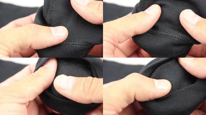 人手测试薄黑色合成织物保暖内衣，特写 (宏观)，拉伸试验