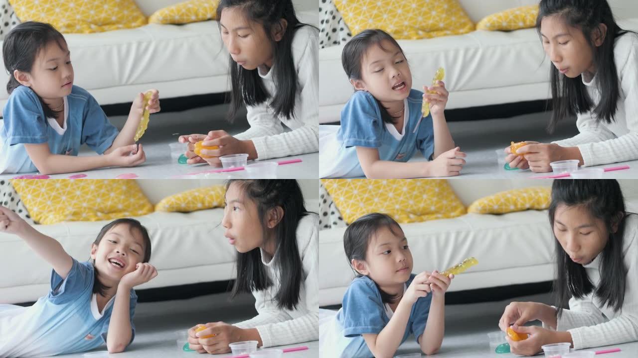 快乐的亚洲女孩一起坐在家里的地板上玩粘液或玩具粘土，生活方式的概念。
