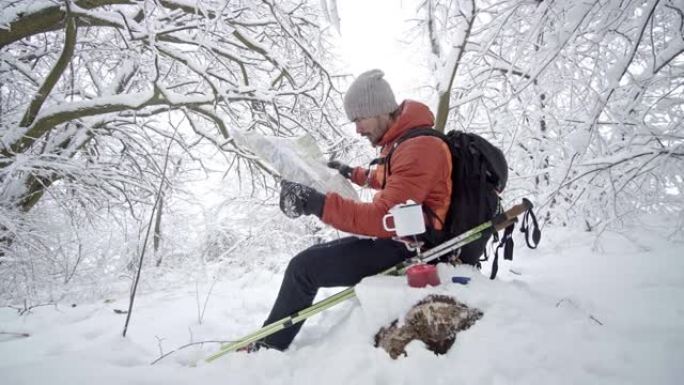 徒步旅行者在茶歇的雪山检查地图